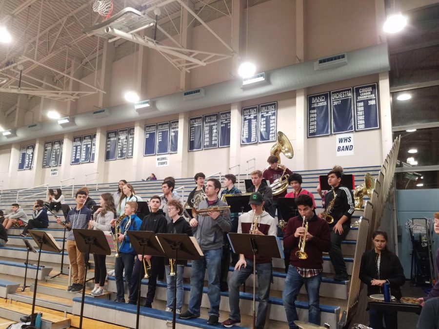 The pep band performing at a basketball game, comprised of symphonic, jazz, and concert ensemble members. 