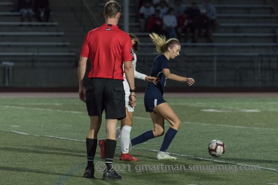 Girls soccer referee gets close to the action. 