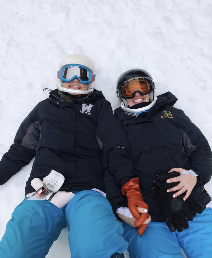 Cailin Gahan, WVHS ski team legend, smiles with a friend while laying in the snow during a practice.