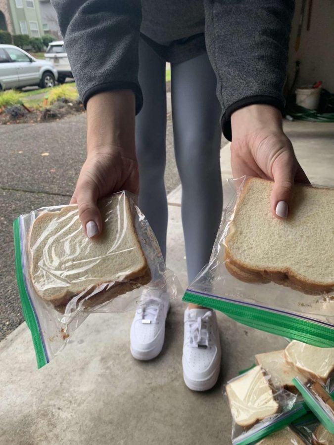 Ellie Wettstein holding peanut butter sandwiches the group made last month. The club organized the sandwiches in the garage before delivering them. 
