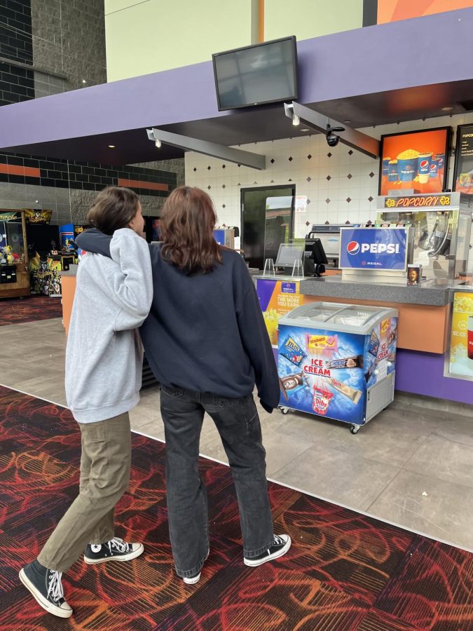 Two teens pick out their snacks in a nearly empty theater. Despite the drop in movie theaters popularity in the past two years, many people have begun to return to the box office for their movie needs.