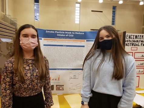 Cassidy and Sophia stand in front of their project board at the CJGSS