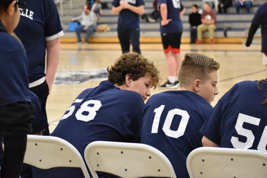 Cole McCanaughy and Robby Peterson, unified partners, sit on the bench waiting to go on the court. 