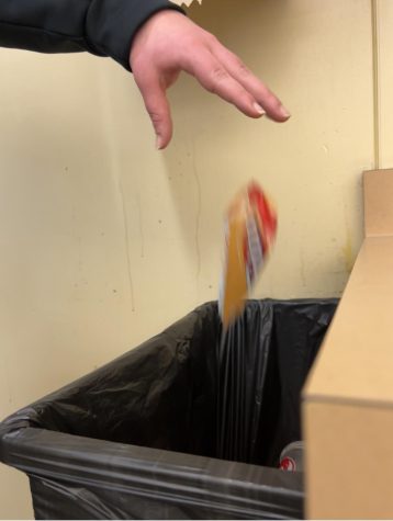 Student at Wilsonville throws their garbage into the trash can. They are leading by example in this school.