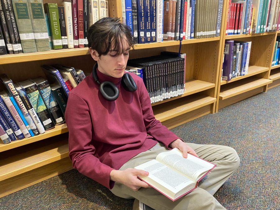 Student Ethan Kessler is calmly reading in his book while sitting in Wilsonville High Schools library. Hopefully more students will join him and indulge their love of reading. 
