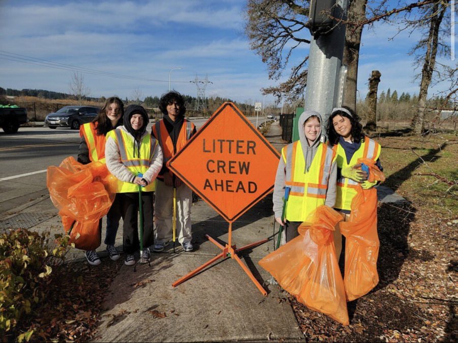 Students in Interact Club helping clean the litter on the road. They wear fluorescent yellow clothing to let drivers know to be cautious driving by.