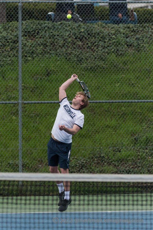 Theo Butchwald serves in a 2022 match. This was before his legendary buzz cut.
