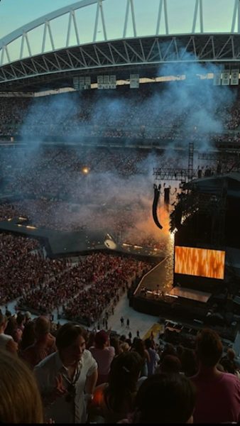 Taylor Swift singing her folklore set, in front of thousands of Seattle fans. The fans excitedly cheer for the singer.