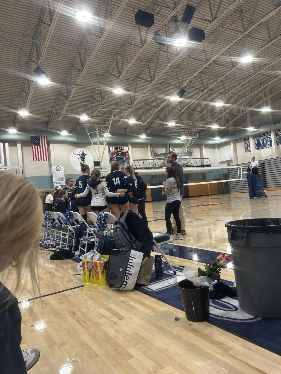 The volleyball team is having a team chat before they begin their fourth set. After winning the second and third sets, they prepared to play hard to win the fourth set and the game.