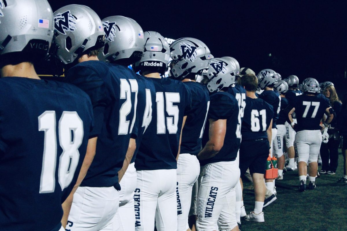 The Cats stand along the sideline, anticipating the final play. With just seconds left, Wilsonville clings to their single-point lead, as players wait to pour onto the field in celebration. 