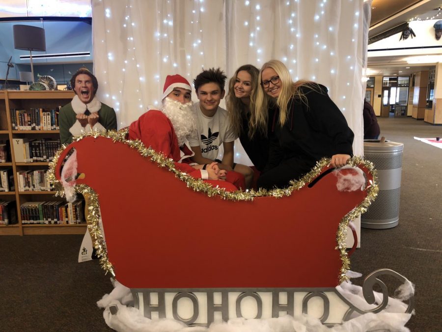 Students Chris Grizzell, Hunter Napoli, Jessica Caulk, and Mckina Stalheim pose in the custom sleigh made for the Wildcat Photo Booth. Students can take pictures in the sleigh up until Winter Break.