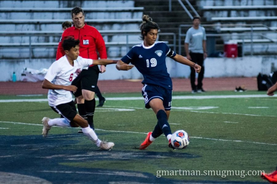 Senior Angel Ulloa takes control of the ball in this tightly contested match.  Despite Wilsonville's fierce offense, the game ended in a tie.