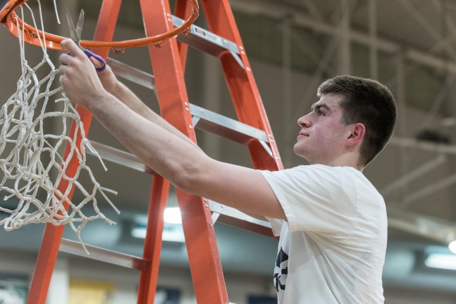 Dakota Reber cuts the net after the playoff win over Corvallis.