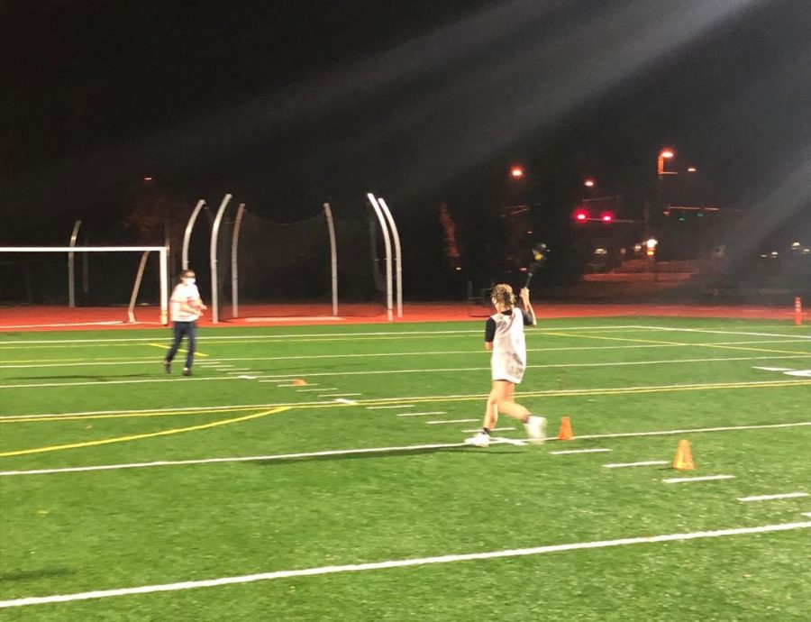 Sophomore Fiona Dunn cradles the ball as she runs towards Senior Maura Schramm, during a Covid-friendly lacrosse practice.