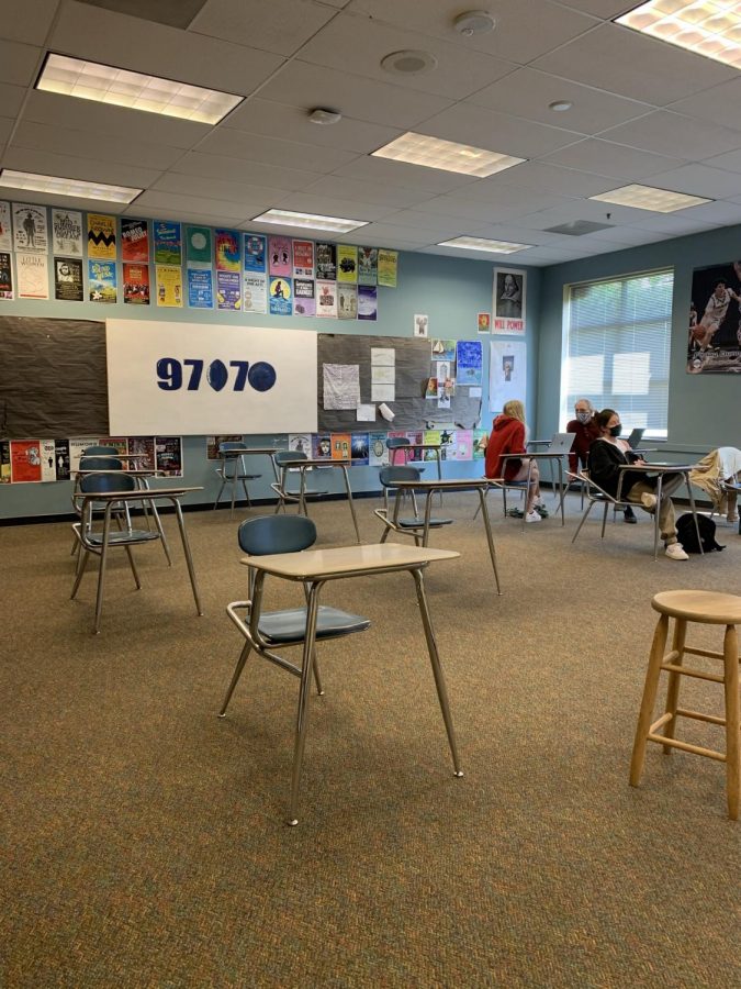 Students collaborate in partially empty classrooms. 