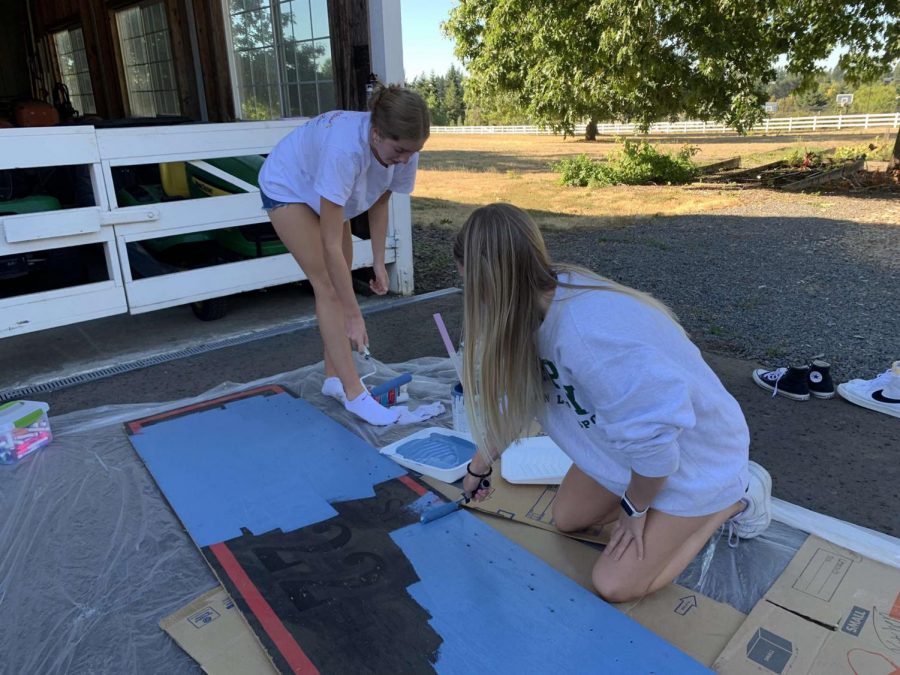 Ellie Wettstein and Piper Colby working hard to paint a sign for the senior float.