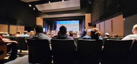 Audience takes pictures and videos of the band playing on stage.