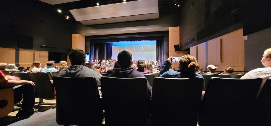 Audience takes pictures and videos of the band playing on stage.