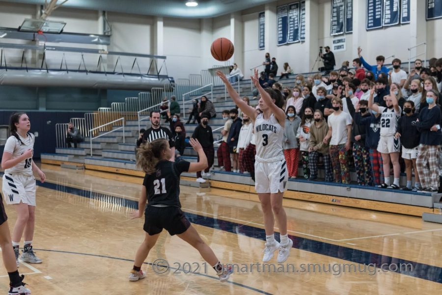 Senior Karina Borgen attempting a three pointer with the support of the student section behind her. 