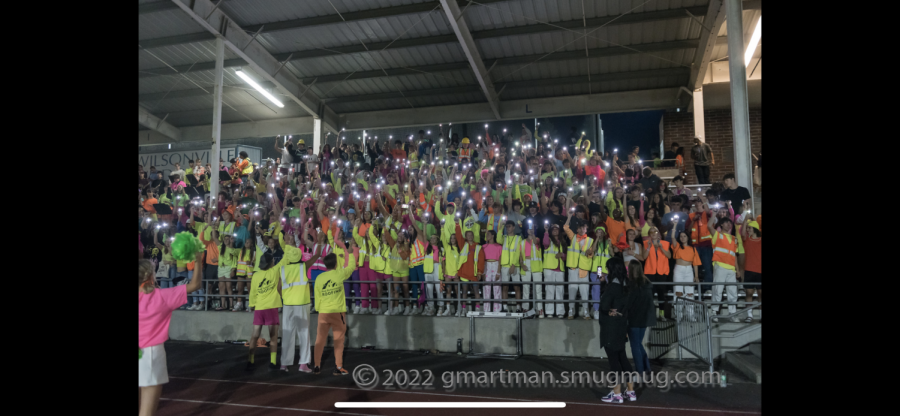 Wilsonville student section during football game. Everyone has their phone flash on is are waving them in the air.    