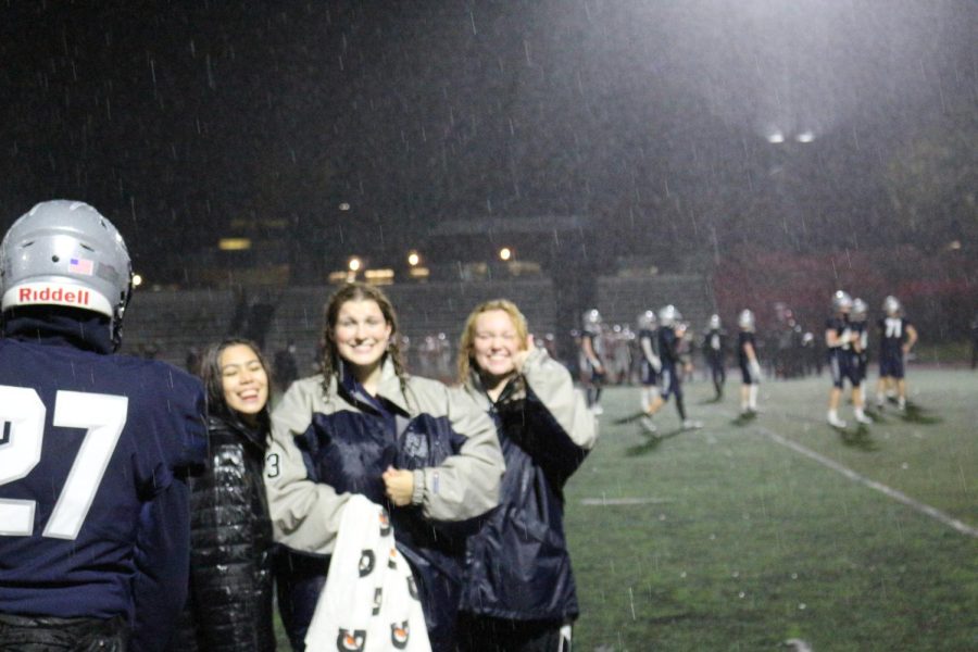 Sky  Wellborn (Left), Grace Friedman (Middle) and Keely Sanford (Far right) posing after speaking about Football. Despite the weather, they smile as they take the "W" against North Eugene.