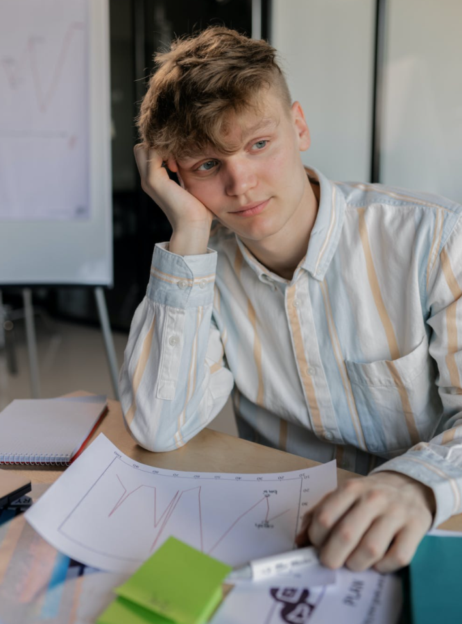 A student spaces out, bored with their studies. The repetitive nature of schoolwork leaves him worn out.