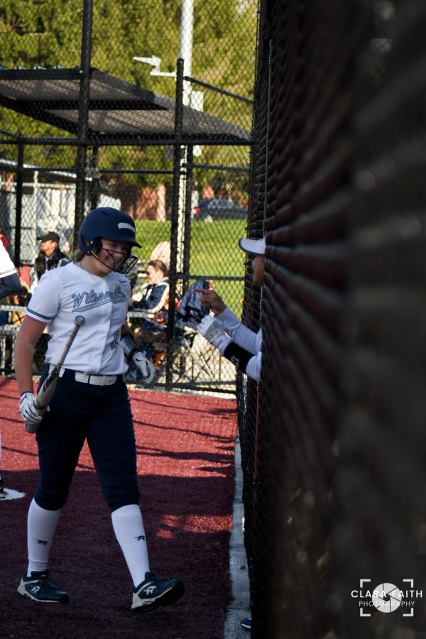 Senior Taylor Hadden congratulates freshman Bailee Van Meter as she comes back into the dugout from the third inning. Bailee is one of the five freshmen on varsity, and she is consistently in the Wildcats' batting line up.   