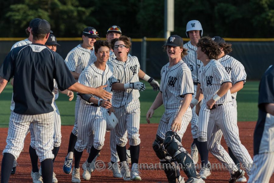 Berkley Reents is swarmed by team mates after hitting a walk-off single. Reent's RBI gave Wilsonville its second straight NWOC title.