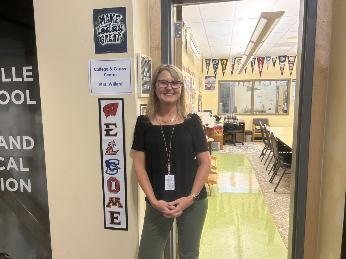  Mrs. Willard, photographed by Grace Kelso. Making sure students know where to find her, she poses by her office sign.