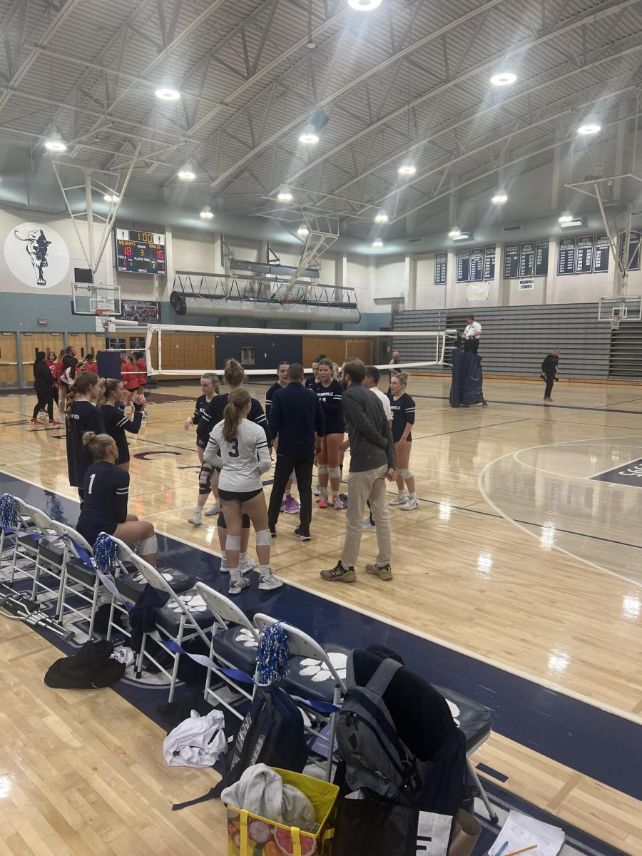 The team huddles up to discuss during a time-out. The set score is close, but Wilsonville goes on to maintain their lead. 

