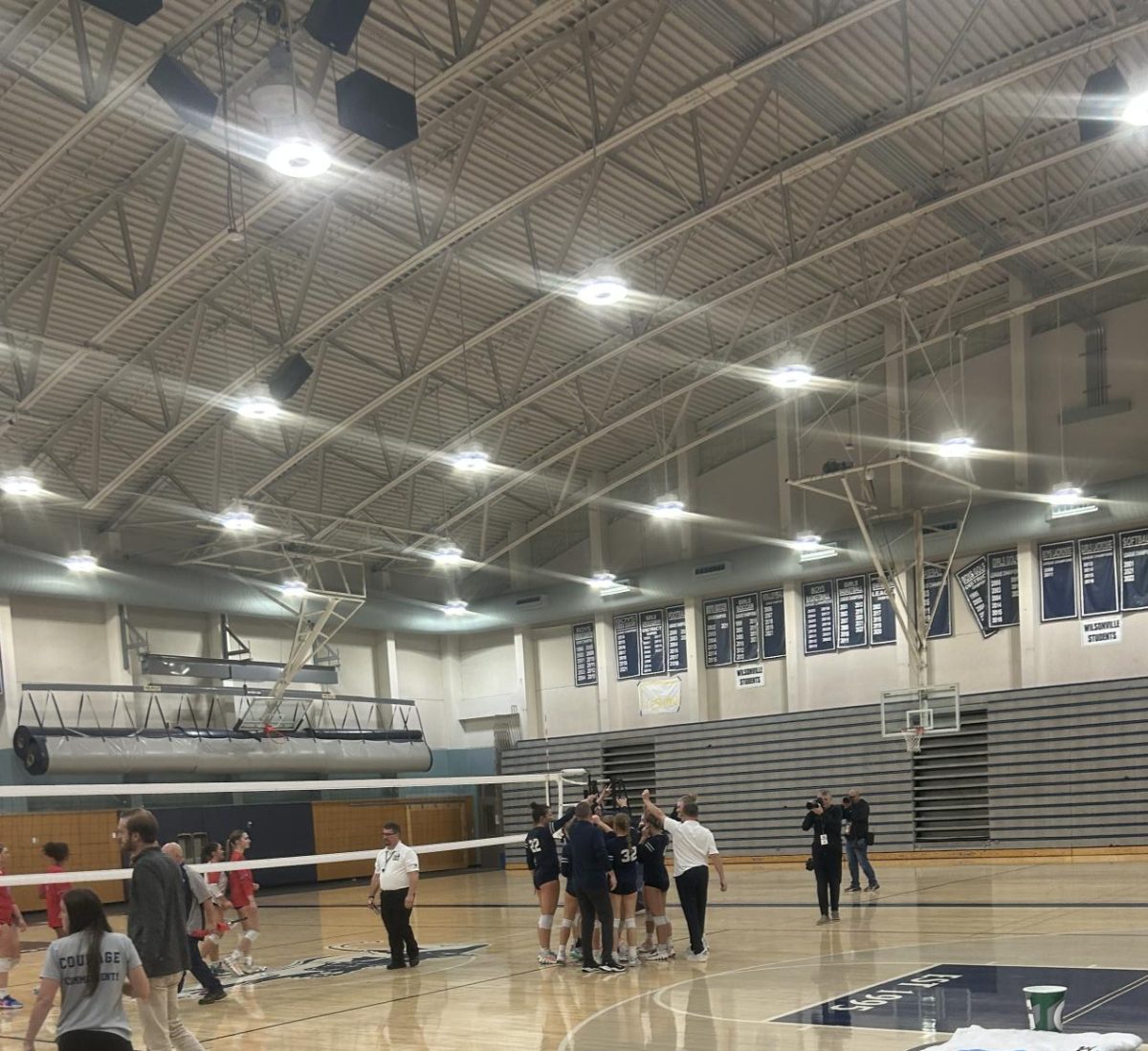 Wilsonville's volleyball team are seen celebrating together. After powering through an eventful four sets, they win the game.