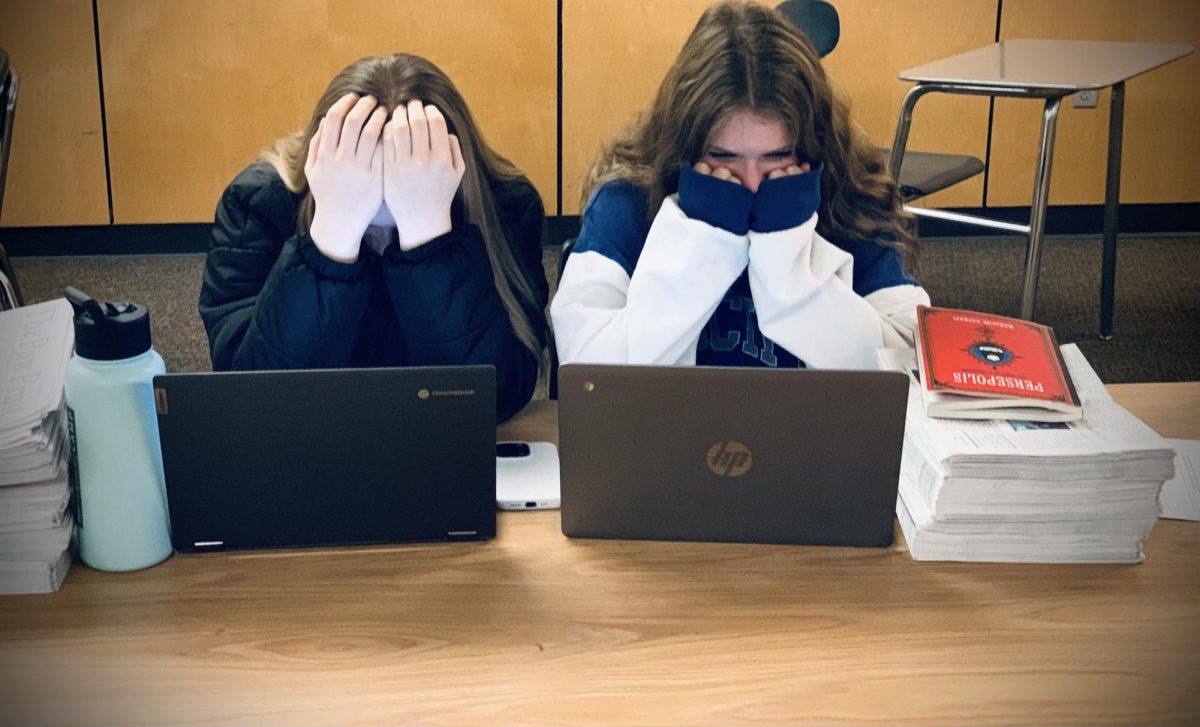 Sophomores Halle Harris and Kylie Weisgerber stress over their piles of schoolwork. They try to focus diligently outside the classroom to complete assignments, but can't help thinking about the loads of homework they'll have later. 