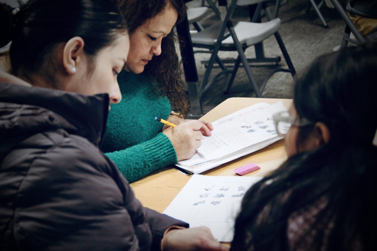 Community members join Monday night's Family Empowerment Program session. A family practices newly-learned English grammar skills in practice books and converses fluently with the instructor.