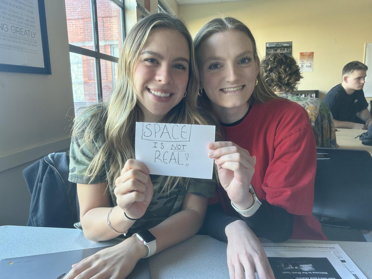 Seniors Ashlyn Hartford and Cammy Gore hold a sign featuring an extremely hot take. This can be an example of the hot takes heard around the halls of Wilsonville High School.