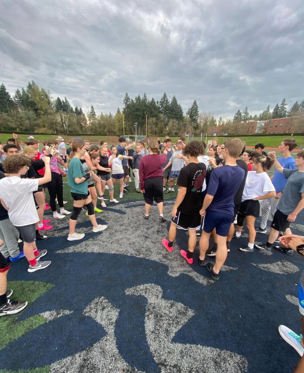 The track and field team meet in the middle of the field for a mid practice huddle. Motivating each other for the rest of practice. Photo provided by Kiera Easterly.