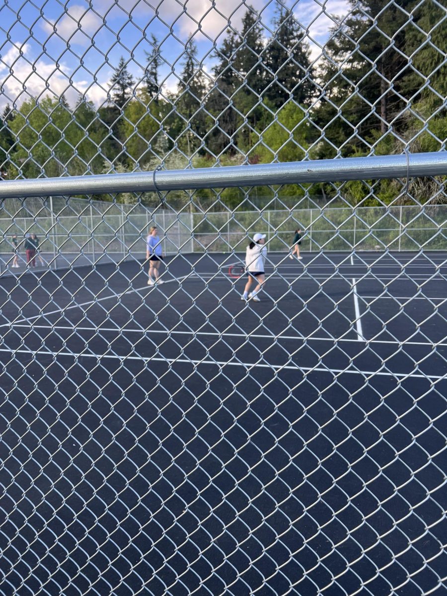 Senior Mattison Quinn and teammate Paula Rumayor practice after a match against Rex Putnam. They later cheered on the other members of the tennis team before they finished their match. 