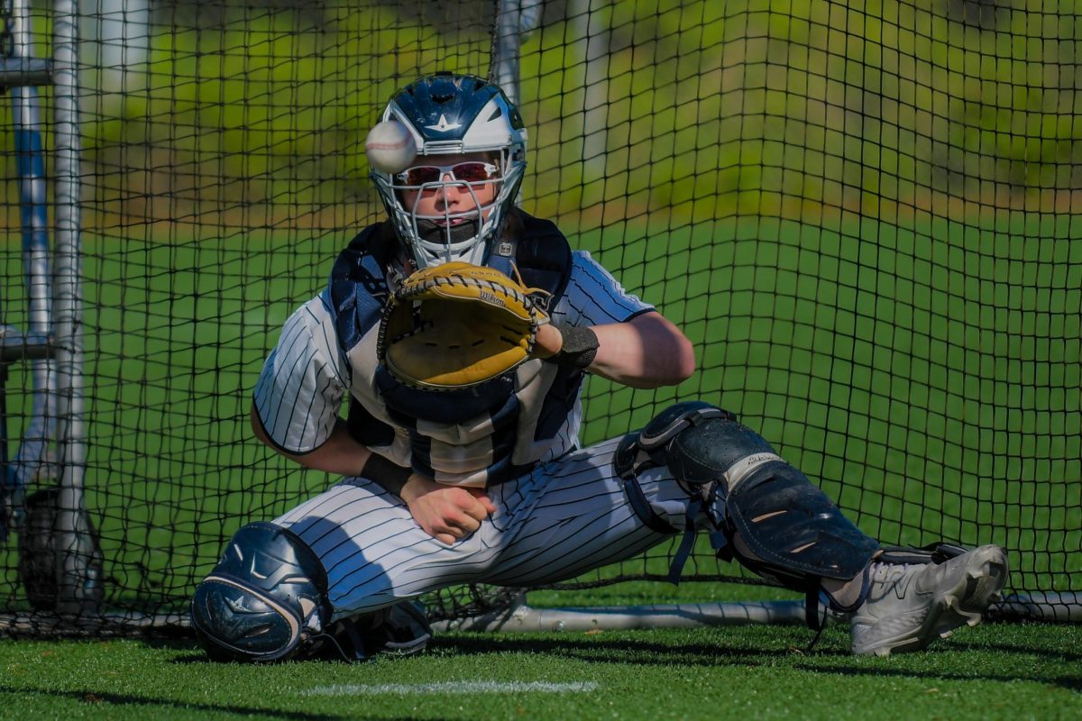 Mark Wiepert warming up a pitcher before the game. Wilsonville baseball has purchased the PitchCom device and has utilized it a couple of times in games. Photo provided by Greg Artman. 