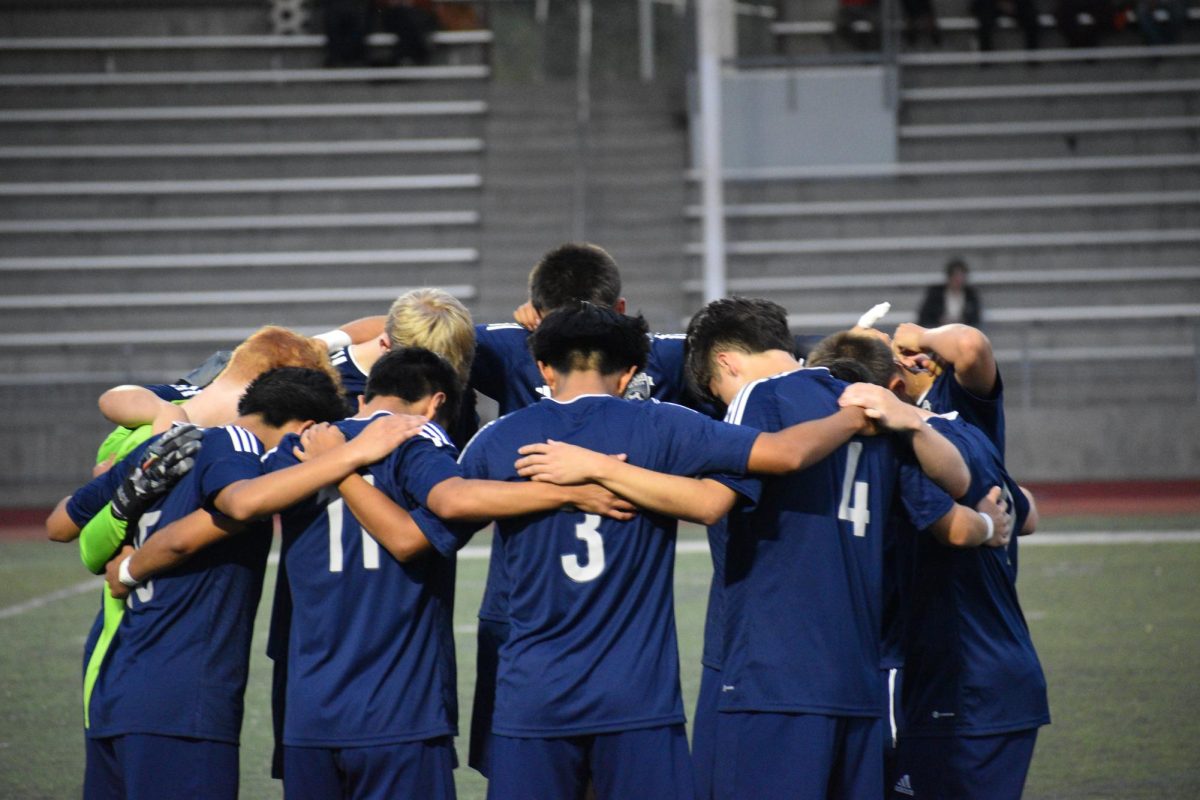 Wilsonville boys varsity team huddles together before the game. Heads bowed and arms around one another, they lead each other in setting up a winning mentality and feeling the adrenaline seep between them. 