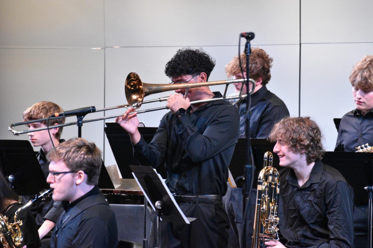 Senior Yahir Corona trumpets away, his solo requiring a high level of focus. Students surrounding him prepare for the next portion of song they will play in. 