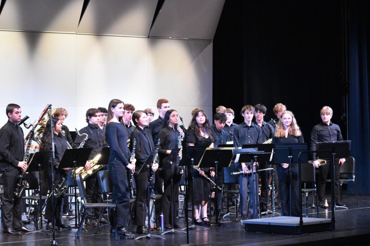 Student musicians stand as a form, bowing. The crowd erupts with cheers, displaying their enjoyment for every moment of the concert. 