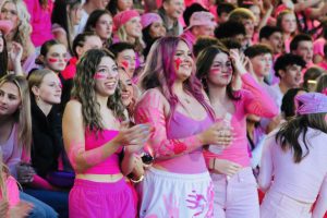 Persia Bowman, Quinn Gann-Winslow, and Bianca Pinoli cheer the Wilsonville football team on in the pink-out homecoming game against Canby. Supporting the team alongside the cheerleaders and hundreds of peers, they proudly shout the chants and follow along in excitement throughout the night. 