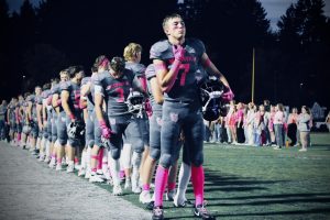 Proud Wildcat, Carter Christiansen, stands as the head of a Wildcat football train. Lining the field in honor of the flag, the Cats stand in the presence of a live vocalization of the National Anthem.