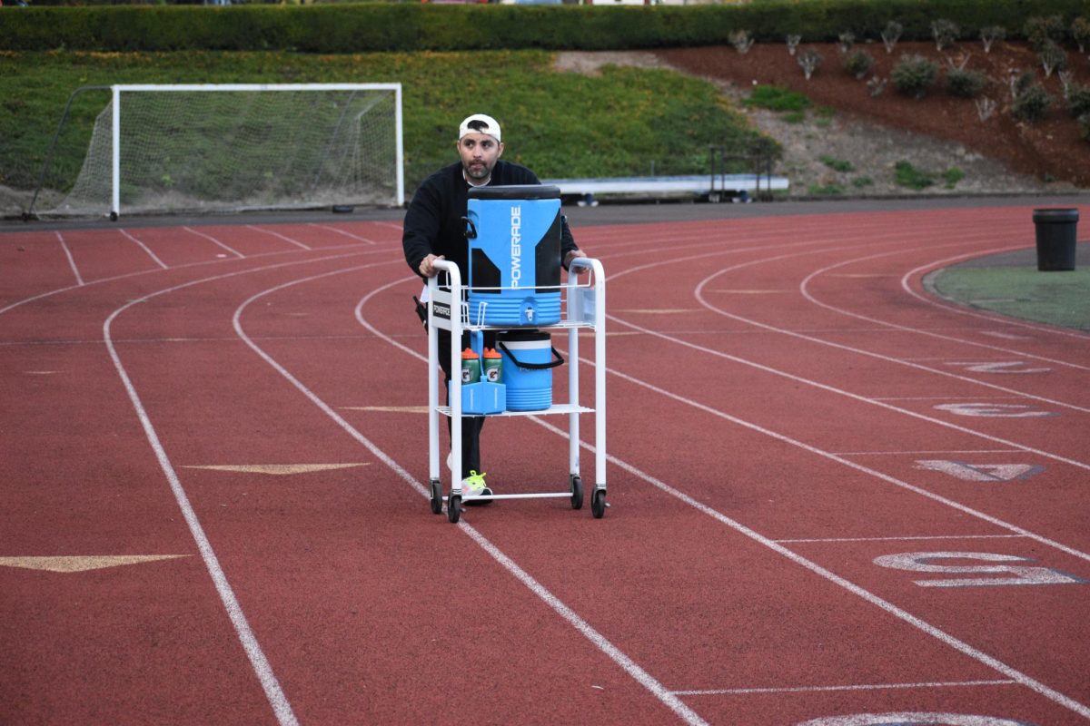 Athletic trainer Jorge Chaires walking out to provide athletic teams with water. His support for all athletes is greatly valued here at Wilsonville High School.