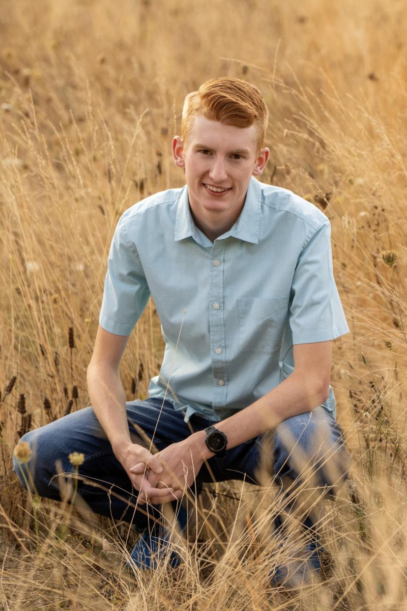 Senior Parker Fish poses in a field for his senior portrait. Photo provided by Parker Fish.