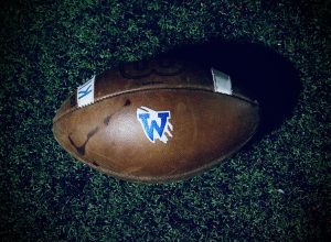 The Wilsonville football lies with the backsplash of turf pebbles and cleat marks. Used tenderly in many practices and games, the ball represents the blood, sweat, and passion put into the game. 