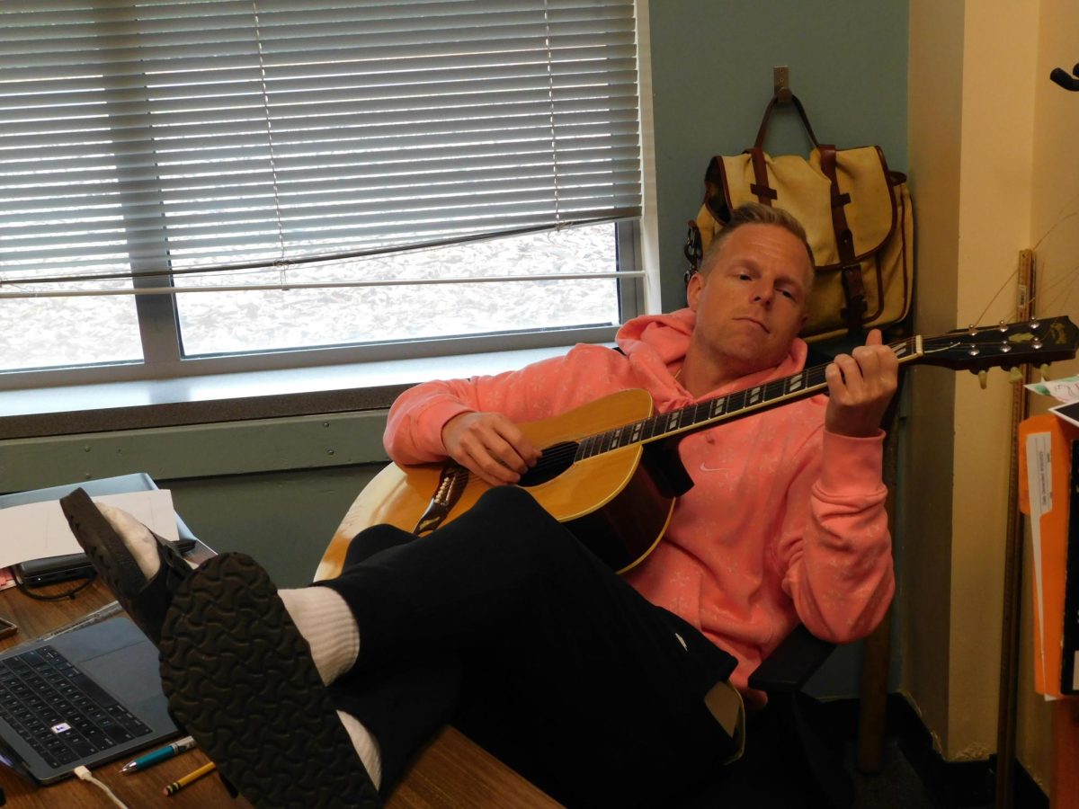 Wilsonville teacher Tyler VanAcker plays the guitar in his classroom. Music is a central part of VanAcker's life, and has been since his childhood.