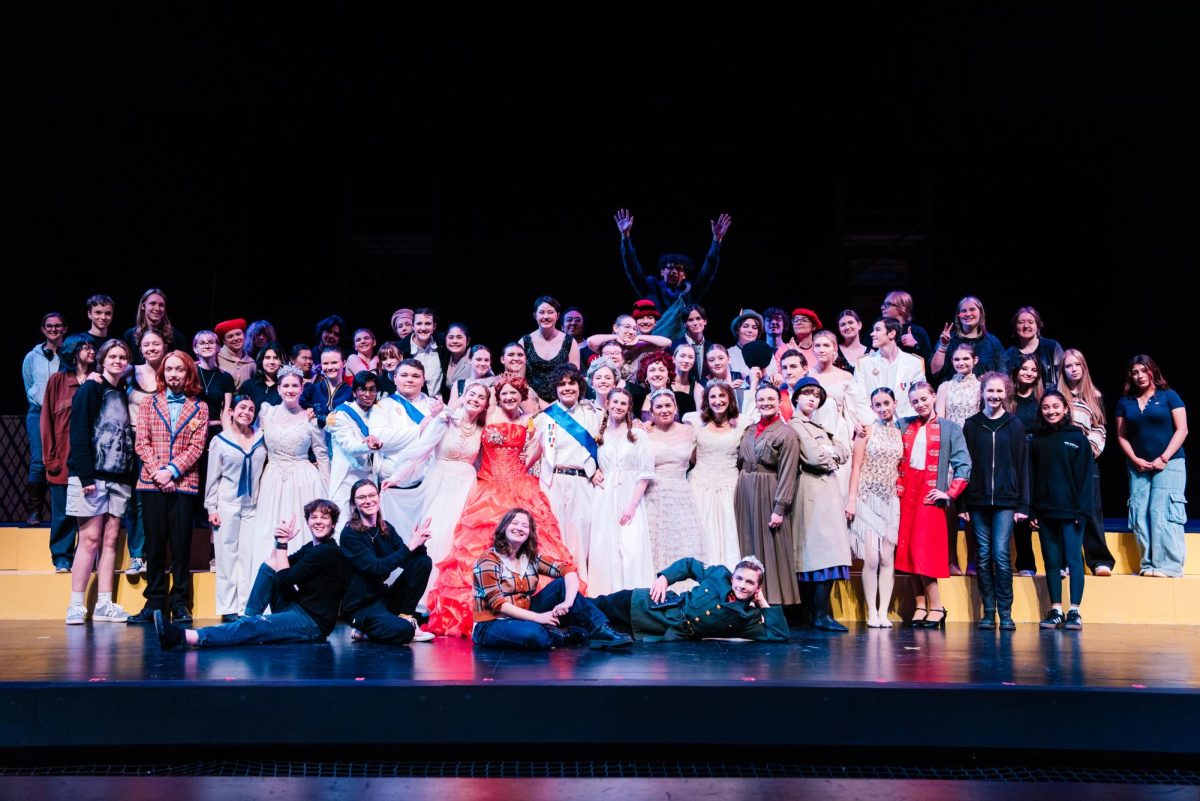 Cast and crew of Anastasia smile as they get in close to fit the frame of the camera. Gyovani Andrade-Angel can be seen jumping for joy in the back. 