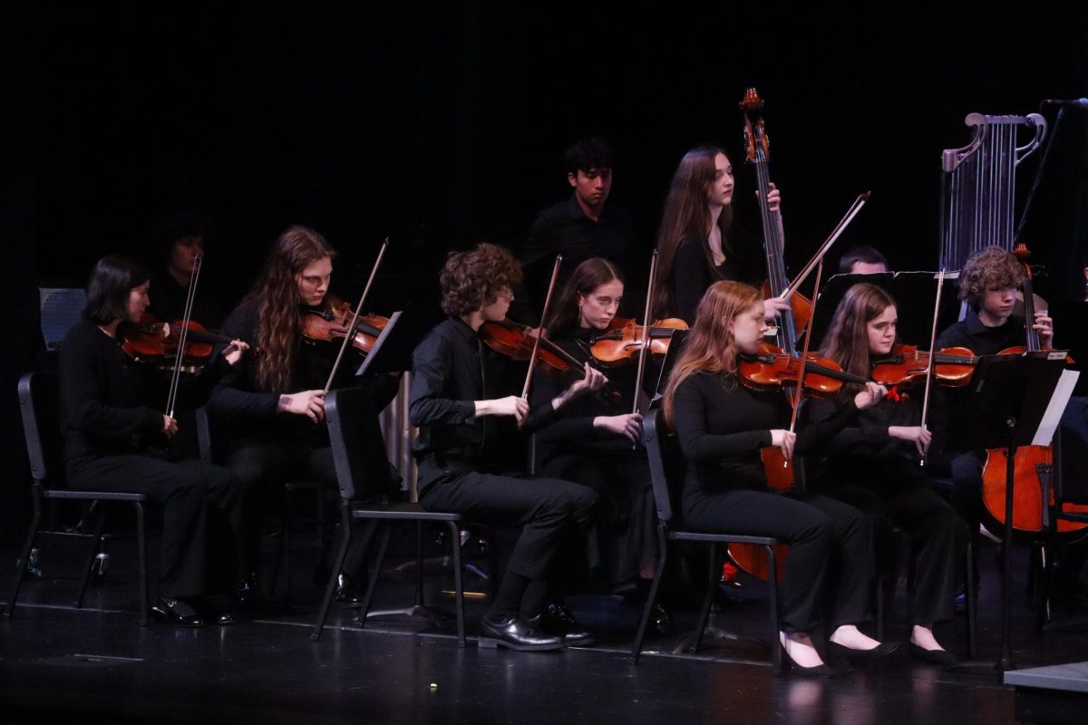 Members of Chamber Orchestra play Christmas Triptych by Ian David Coleman. Connected through the music, each member holds their bow at the same angle. 