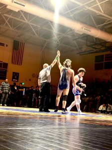 Senior Charlie Middleton's hand is raised, declaring victory in Milwaukie. The wrestling team overall shows aggressiveness on the mat, and leadership in the program. Photo provided by the Wilsonville High School wrestling team.