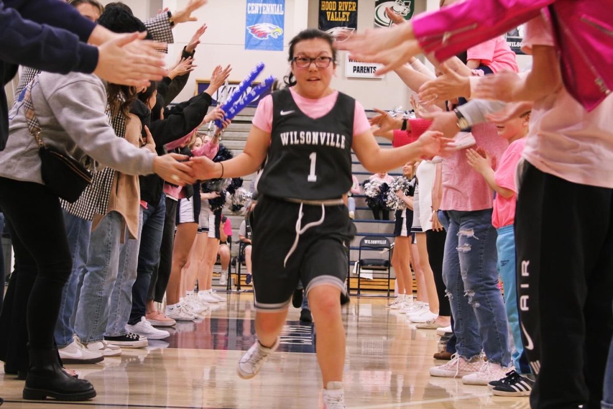 Wilsonville senior, Reagan Meister, runs down the tunnel of supportive parents, cheerleaders, friends, coaches, and admin. High-fiving each person as she runs down the alley, Meister celebrates her senior night with her team.